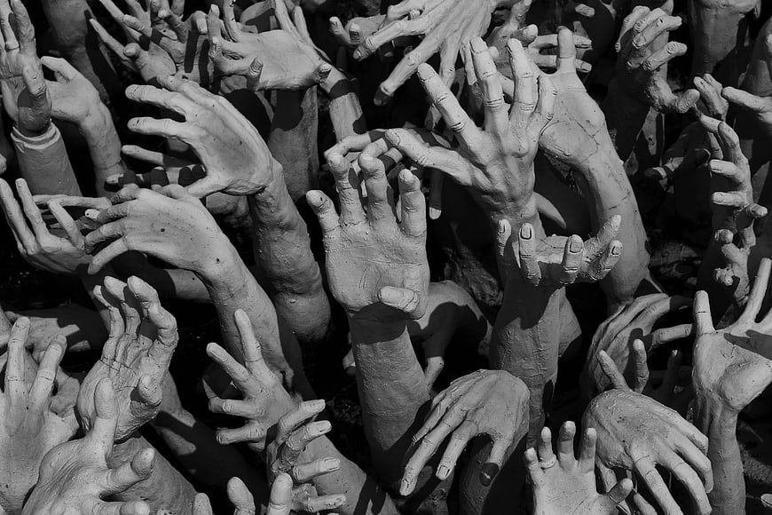 Black and white photo of reaching hands sculpture in Thai Buddhist hell