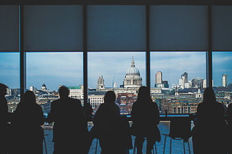 Silhouettes of people looking at London skyline from window