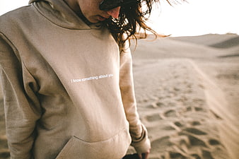 Woman in beige hoodie with text in desert landscape