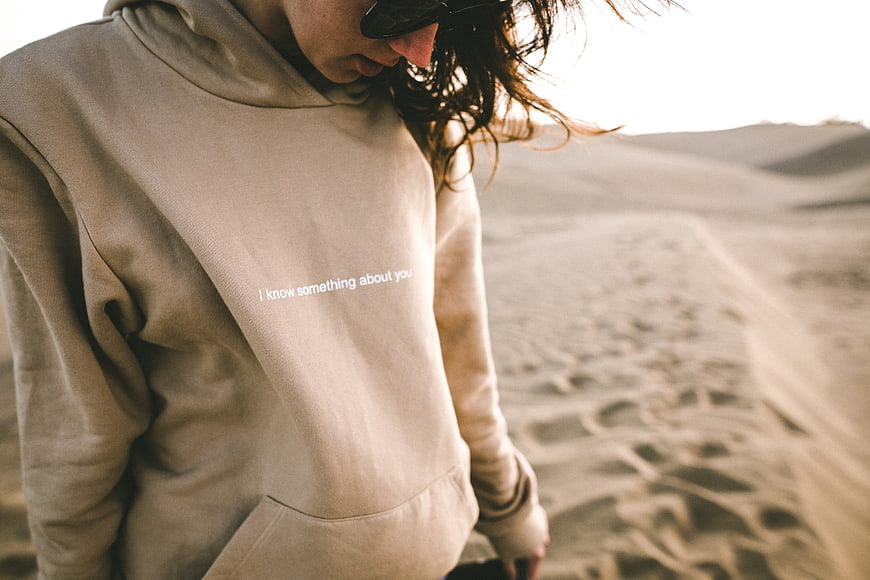 Woman in beige hoodie with text in desert landscape