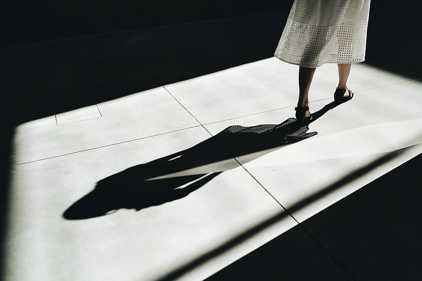 Woman's Legs and Dramatic Shadow on Sunlit Concrete Floor