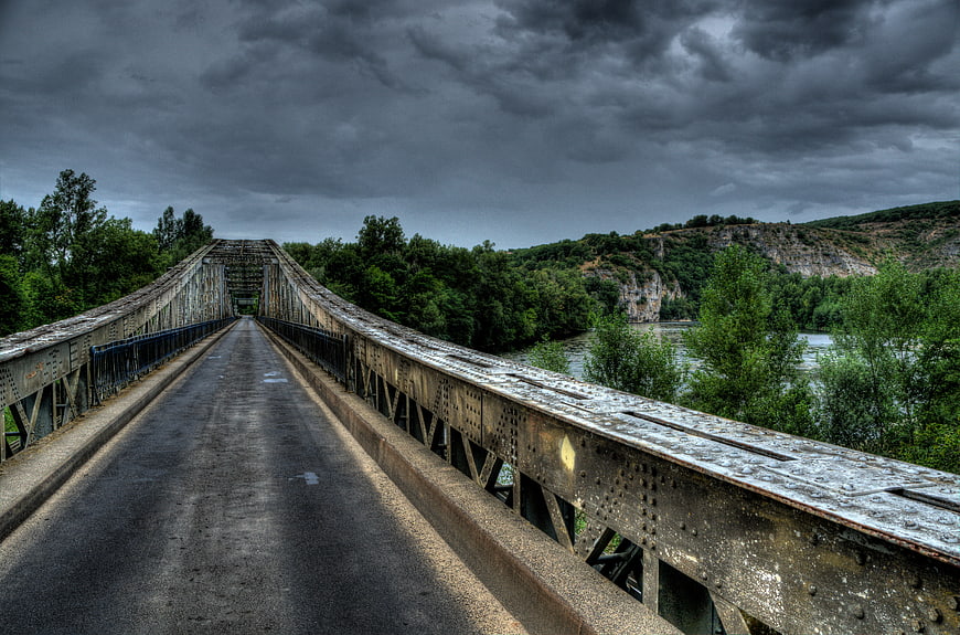 Dramatic HDR view of old metal bridge over river
