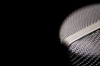 Close-up of silver microphone grill on black background
