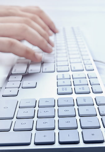 Close-up of hands typing on a white computer keyboard