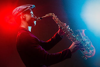 Jazz musician playing saxophone under dramatic red and blue stage lighting