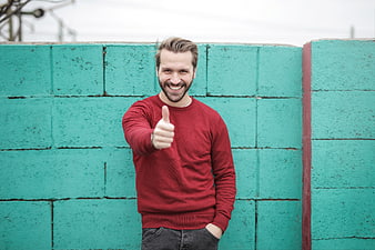Happy Man Giving Thumbs Up Against Teal Brick Wall