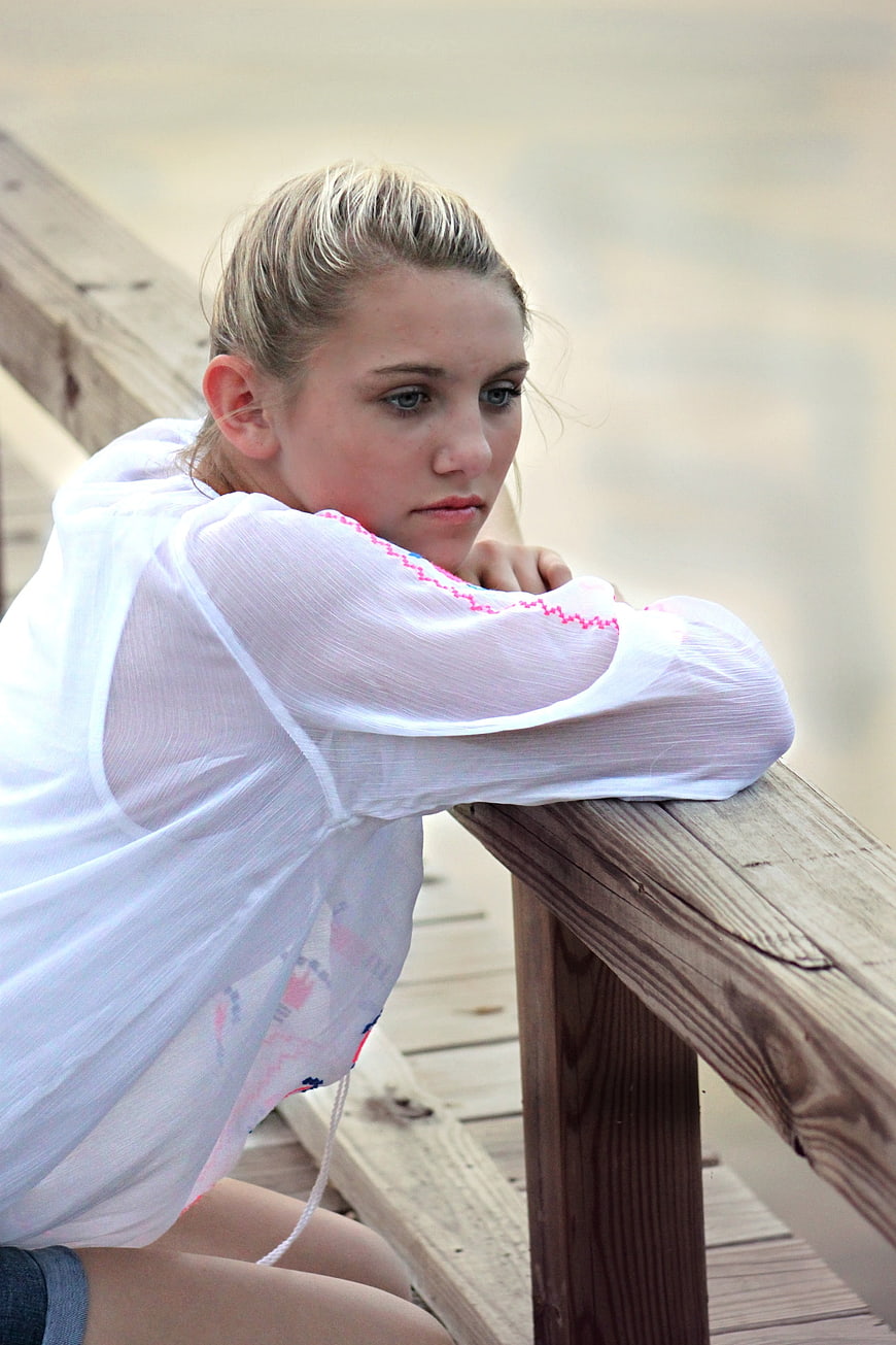 Pensive young woman leaning on wooden railing outdoors