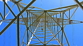 Low angle view of steel electricity pylon against blue sky