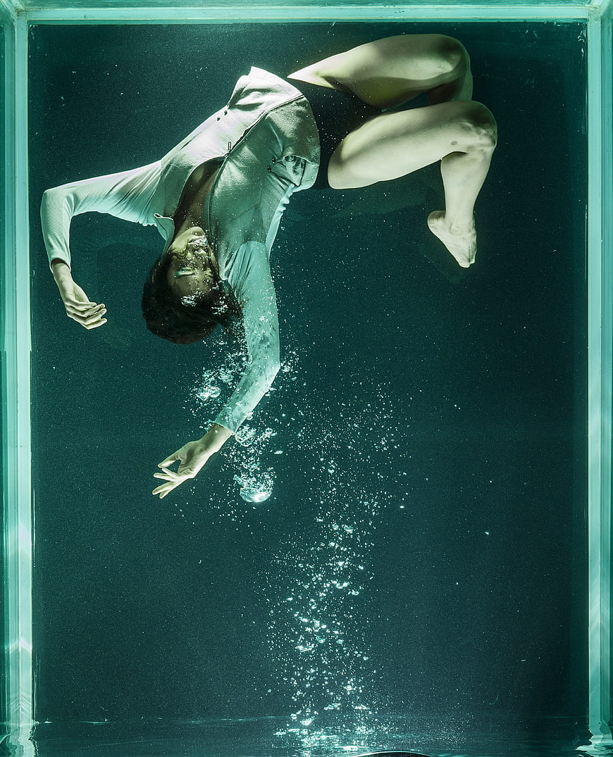Woman Floating Underwater in Tank with Bubbles