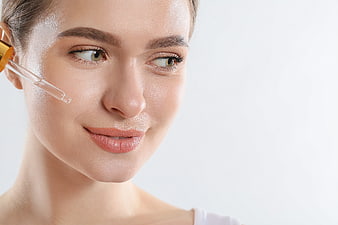 Woman applying serum dropper to face skincare