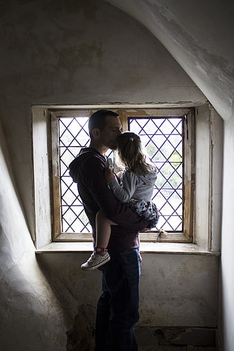 Father kissing daughter in rustic attic window