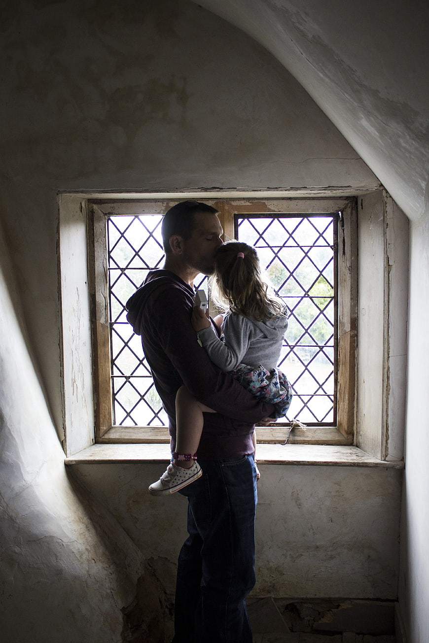 Father kissing daughter in rustic attic window