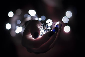 Hand Holding Glowing String Lights with Bokeh Background