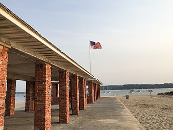 American Flag Flying Over Brick Pier at Beach