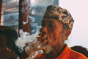 Senior man smoking cigarette with traditional headwear