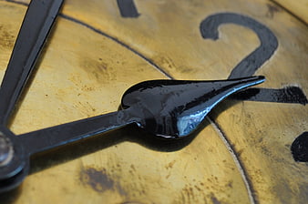 Close-up of vintage clock hands on aged yellow face