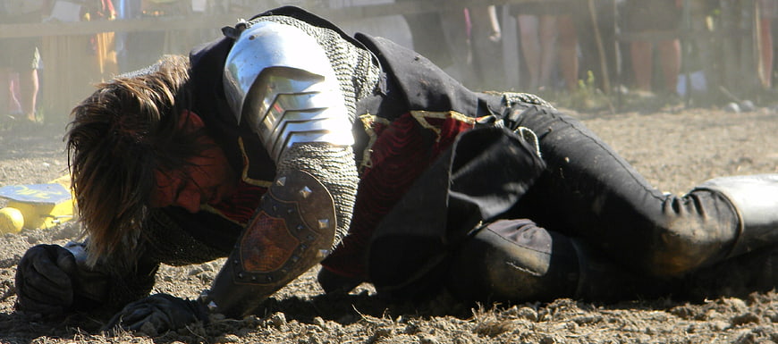 Exhausted Medieval Knight Collapsing on Dusty Battlefield