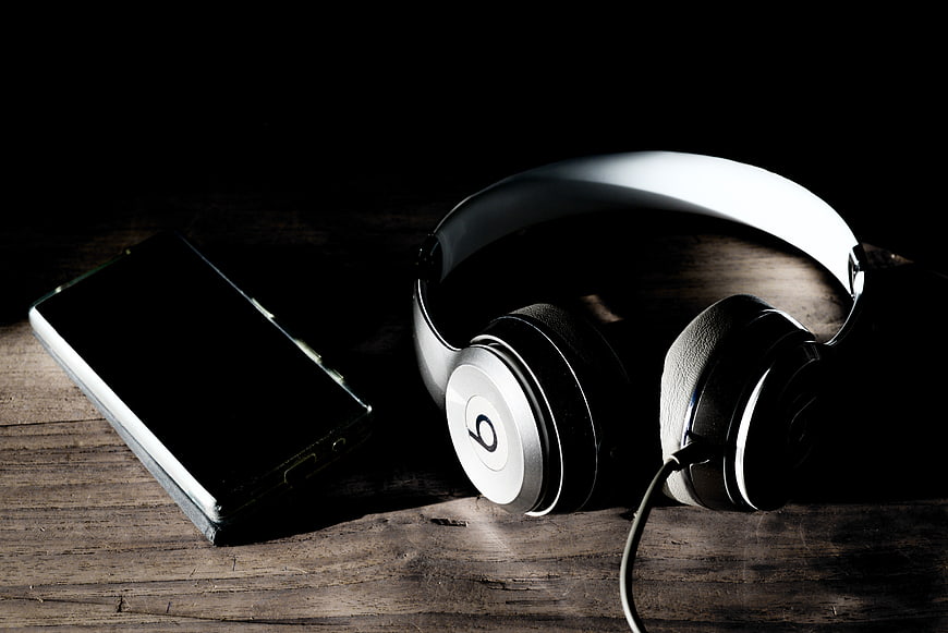 Silver headphones and smartphone on dark wooden table
