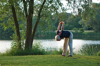 Senior man stretching by a lake in nature