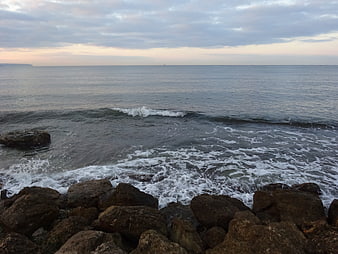 Rough Ocean Waves Crashing on Rocky Shore at Dusk