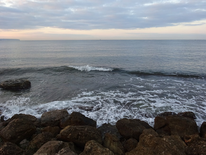 Rough Ocean Waves Crashing on Rocky Shore at Dusk