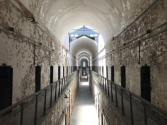 Abandoned prison corridor with peeling paint and barred cells