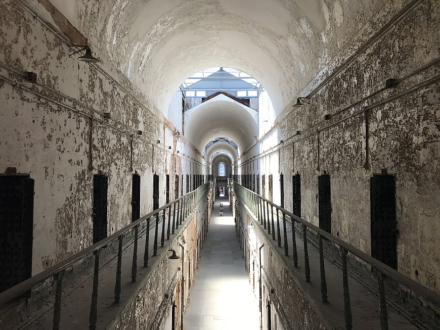 Abandoned prison corridor with peeling paint and barred cells