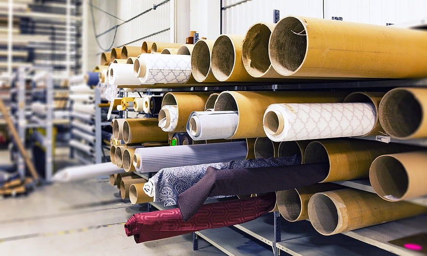 Rolls of patterned fabric on industrial warehouse shelves