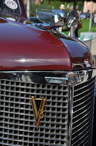 Close-up of vintage red Cadillac V8 grille and hood ornament