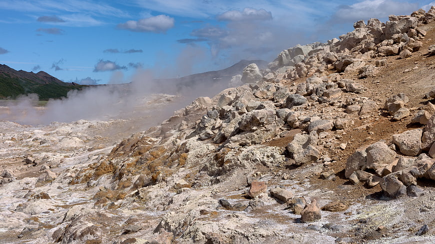 Rugged volcanic landscape with steam vents and rocky terrain