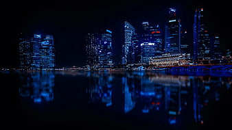 Illuminated City Skyline Reflected in Water at Night
