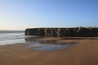 Serene coastal landscape with sandy beach and cliffs
