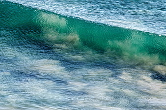 Aerial view of turquoise ocean wave crashing with white foam