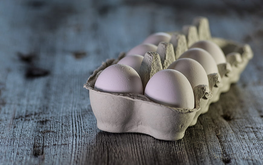 Carton of fresh eggs on rustic wooden table