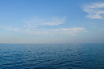 Serene Blue Ocean Horizon with Wispy Clouds and Moon