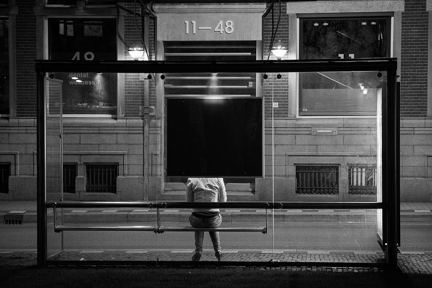 Lone figure waiting at a bus stop at night
