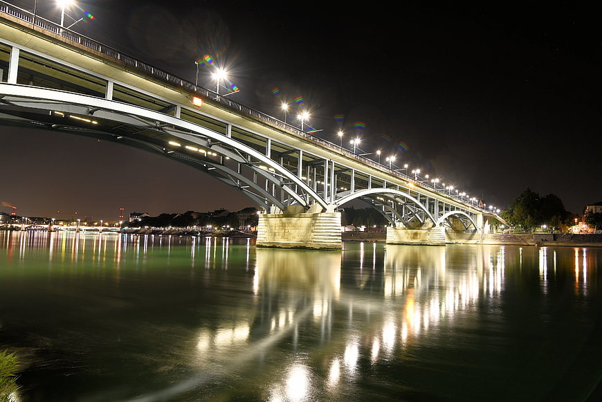 Illuminated steel arch bridge over river at night