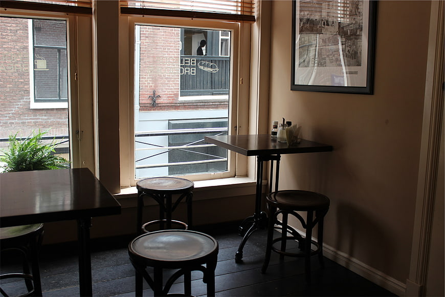 Cozy cafe interior with wooden tables and stools by window