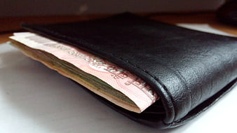 Black leather wallet with Indian rupee banknotes on a white surface