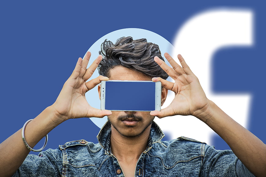 Man holding smartphone in front of Facebook logo background