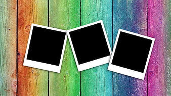 Three empty polaroid frames on colorful painted wooden background