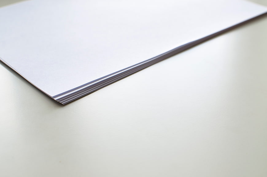 Stack of white paper on a clean desk surface