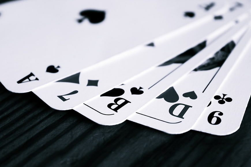 Black and white close-up of fanned playing cards on dark textured surface