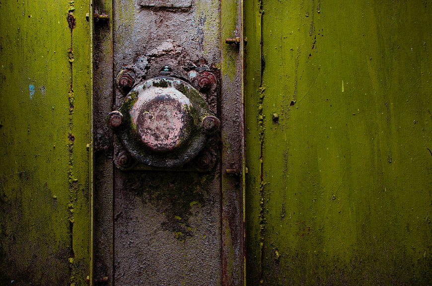 Close-up of rusty metal lock on weathered green steel door