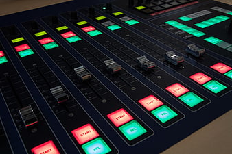 Close-up of professional audio mixing console with illuminated faders and buttons