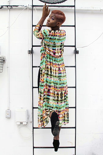 Woman in Colorful Dress Climbing Urban Ladder