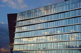 Modern Glass Skyscraper Reflecting Blue Sky and Clouds