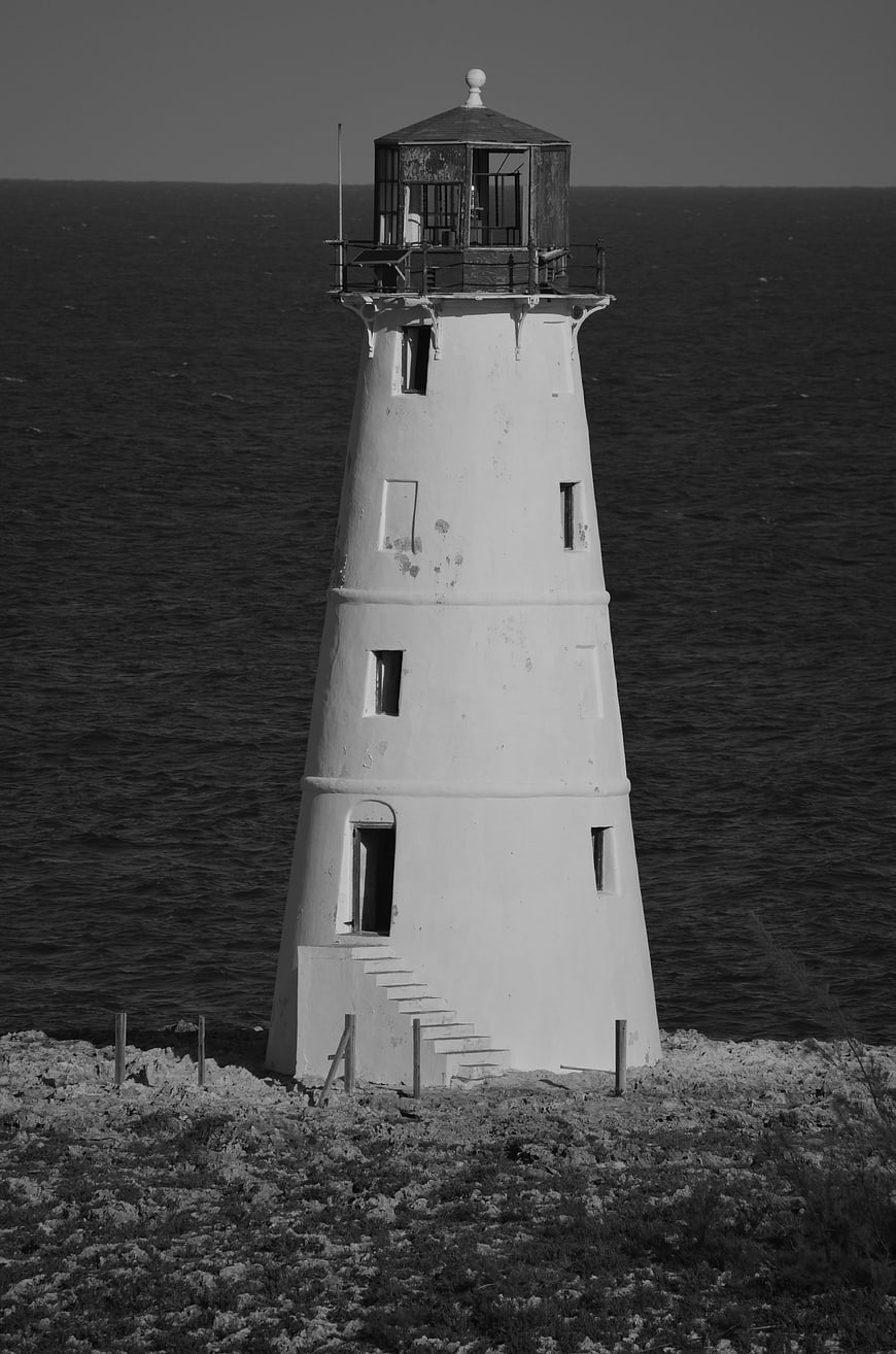Black and white lighthouse on rocky coast by the sea