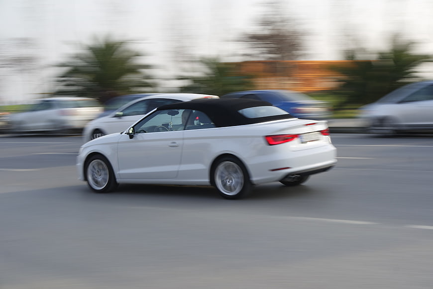 White convertible car driving fast on city street