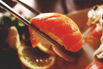 Close-up of Salmon Sushi Held by Chopsticks